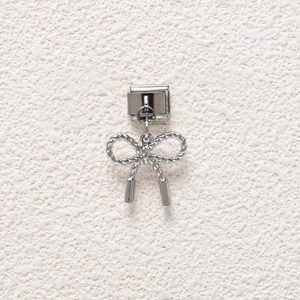 Close-up of a silver bow charm with woven texture for modular Italian style bracelets