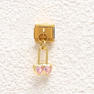 Detail of gold modular link charm featuring a lock pendant with two pink heart crystals