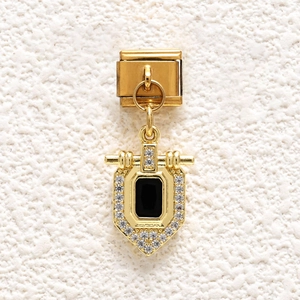 Macro detail of gold-plated shield charm with black stone and pave crystals on modular link