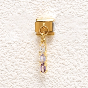 Macro detail of gold-plated stainless steel charm with triple oval purple gemstones