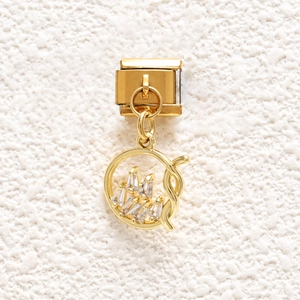 Close-up of golden Italian charm link with hollow circular crystal crown pendant