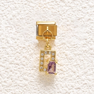 Macro detail of Italian charm bracelet link with gold plating and purple zircon stone