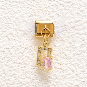Detailed close-up of gold stainless steel modular bracelet charm with pink gemstone