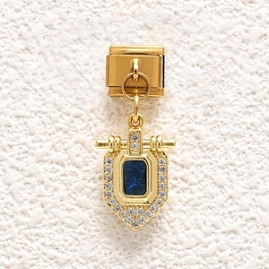 Macro shot of gold Italian charm with rectangle blue gemstone and white pavé crystals