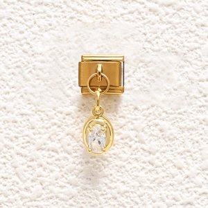 Detailed close-up of a gold modular Italian charm with a clear oval-cut gemstone inlay