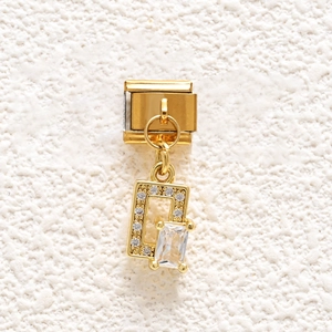 Macro detail of Italian gold charm with pavé crystals and rectangular zircon stone
