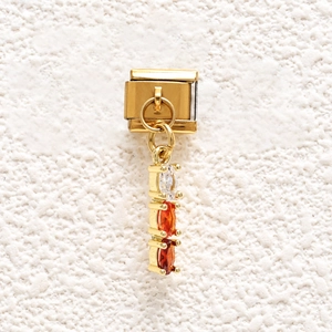 Macro detail of a gold stainless steel modular link charm with triple oval gemstones