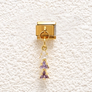 Macro detail of Italian gold stainless steel charm with three purple triangular gemstones
