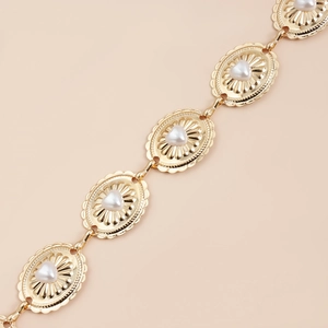 Detailed macro view of golden oval links with heart pearls on bohemian waist chain
