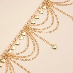 Detail showing multi-layer gold metal chains with polished heart-shaped pendants