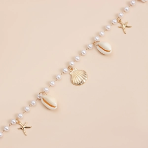 Detailed close-up of pearl body chain with golden starfish and white seashell charms
