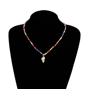 Détail du collier bohème en perles colorées avec un pendentif conque doré