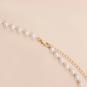 Macro detail of summer pearl waist chain featuring gold lobster clasp and adjustable links