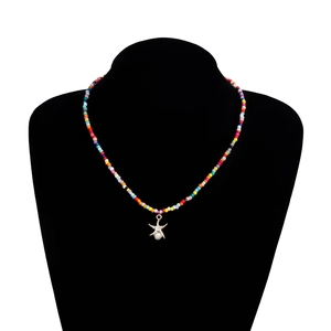 Détail du collier bohème en perles colorées avec pendentif étoile de mer dorée et perle