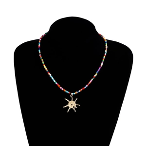 Détail d'un collier de perles colorées avec pendentif soleil doré sur un buste noir