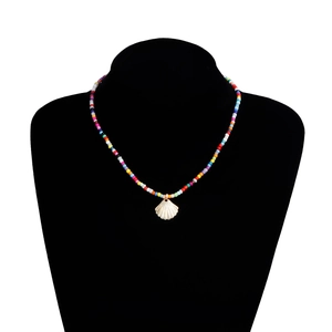 Vue détaillée du collier de perles colorées et pendentif coquillage doré sur buste