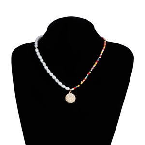 Détail d'un collier bohème avec perles blanches, perles colorées et pendentif vague doré