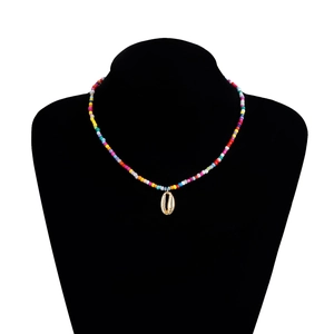 Détail d'un collier de perles colorées avec un pendentif coquillage doré sur un buste