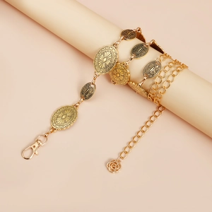 Detailed close-up of vintage gold body chain with engraved charms and a rose pendant