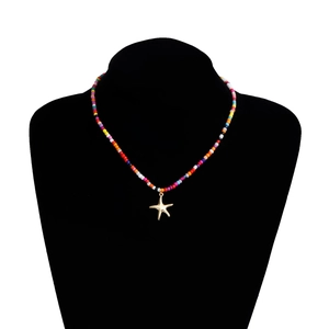 Détail d'un collier de perles multicolores orné d'un pendentif étoile de mer doré
