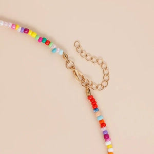 Détail d'un collier bohème en perles colorées avec fermoir mousqueton doré et chaîne