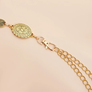 Close-up of vintage gold totem waist chain with ornate metal plate and lobster clasp