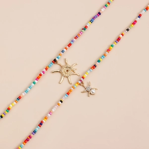 Détail d'un collier bohème en perles colorées avec pendentif soleil doré et breloque étoile