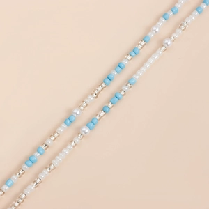 Close-up detail of double-layer light blue and white pearls beach body chain