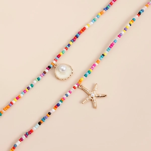 Détail de colliers bohèmes colorés avec pendentifs coquillage et étoile de mer dorés