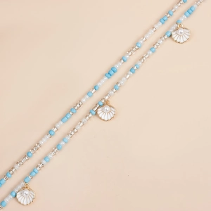 Detailed close-up of blue and white beads with pearl-inlaid shell charms on a gold body chain