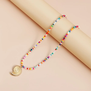 Détail d'un collier d'été bohème avec perles colorées et pendentif en forme de coquillage doré