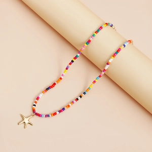 Détail d'un collier en perles colorées avec pendentif étoile de mer dorée style bohème