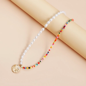 Détail d'un collier bohème avec perles blanches, perles colorées et pendentif pièce dorée