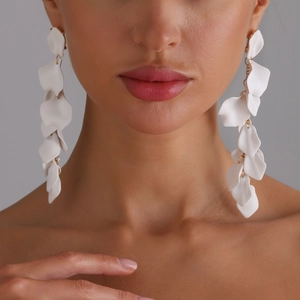 Eleganti orecchini lunghi con petali bianchi opachi e dettagli in oro indossati da modella