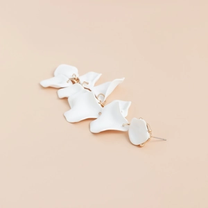 Dettaglio ravvicinato di orecchini a petalo bianco con eleganti inserti metallici dorati