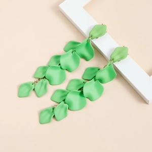Dettaglio di orecchini a petalo verde opaco con maglie dorate su sfondo dallo stile minimal