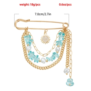 Détail d'une broche dorée bohème avec pierres bleues, perles et pendentif soleil