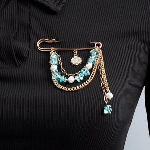 Broche épingle bohème dorée avec pierres bleues et perles sur un vêtement noir élégant