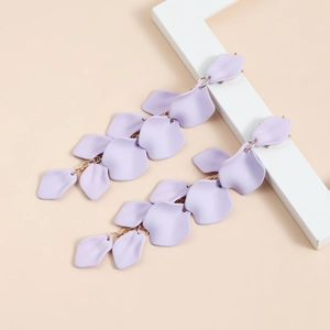 Dettaglio di orecchini a nappa con petali lavanda e catene dorate su sfondo elegante