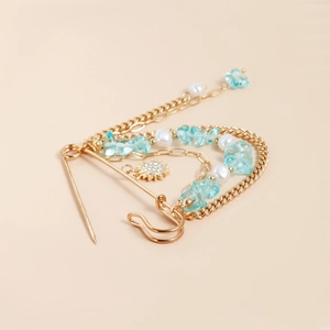 Broche multi-chaînes dorée avec pierres bleues et pendentif soleil élégant