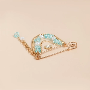 Détail d'une broche épingle dorée avec perles bleues et pendentif en forme de soleil