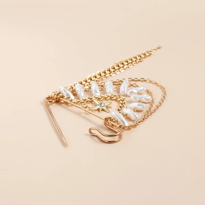 Macro detail of gold layered brooch with pearls, tassels and a sparkling star pendant