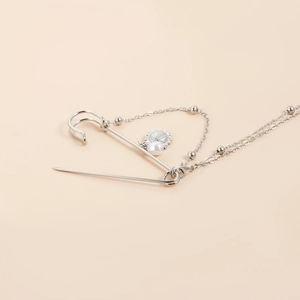 Detail view of silver safety pin brooch with hanging pearl and sunflower pendant