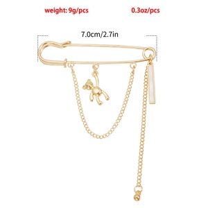 Detailed view of 7cm gold pin brooch featuring a hanging bear charm and white bar pendant