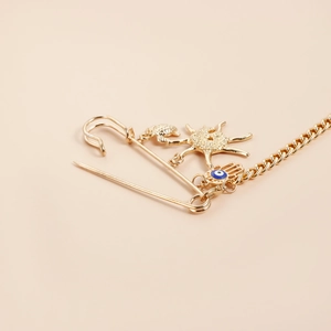 Détail d'une broche dorée avec pendentifs étoile de mer, crabe et main de Hamsa
