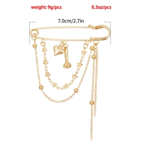 Detailed view of golden multi-layer chain safety pin brooch with heart and star pendants