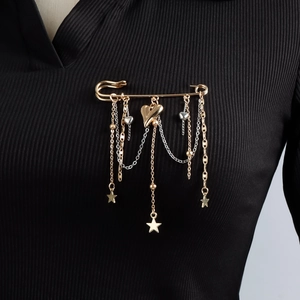 Golden safety pin brooch featuring hanging metal chains, heart charms and star pendants