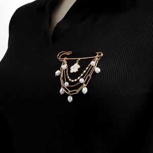 Golden layered fringe brooch with white flower and pearls on black suit fabric