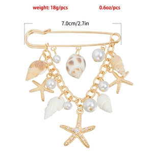 Détail d'une broche dorée thème marin avec pendentifs coquillages, étoiles de mer et perles