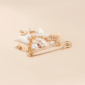 Vue détaillée d'une broche dorée avec coquillages, perles et pendentif étoile de mer